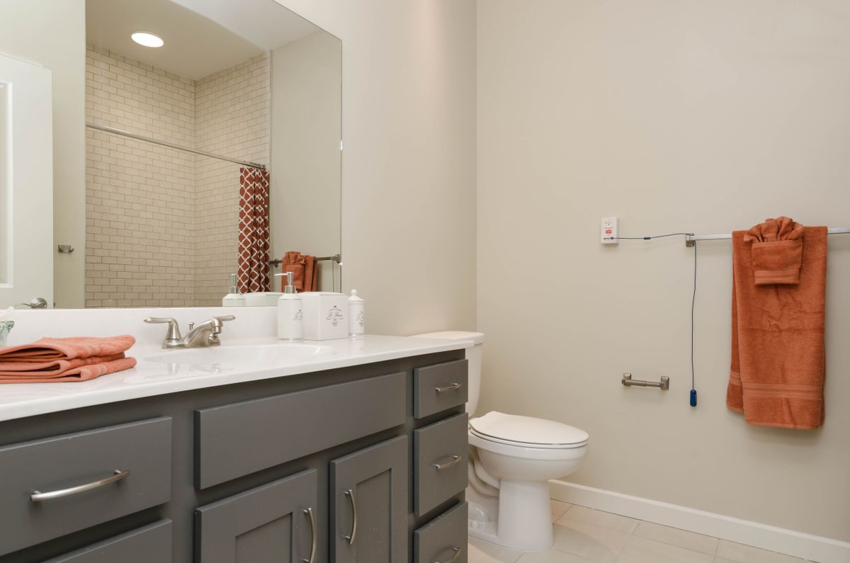 A clean and modern bathroom with a sink, mirror, and toilet.