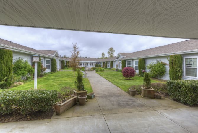 A peaceful courtyard surrounded by buildings and green gardens on an overcast day.