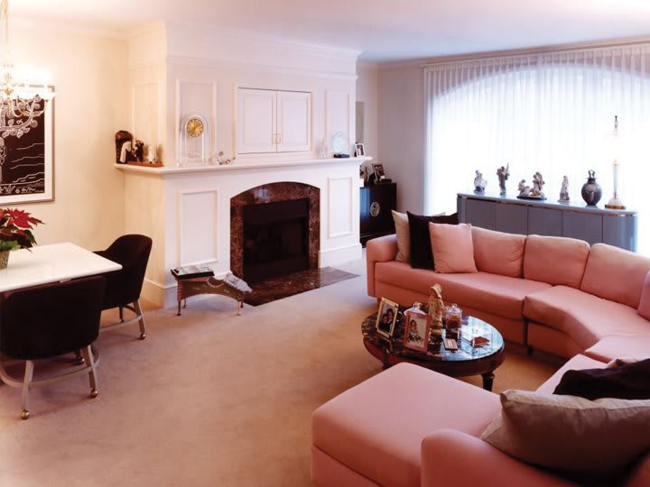 A cozy living room featuring a fireplace, a pink sectional sofa, and a stylish coffee table.