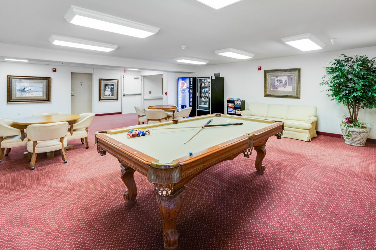 A spacious game room with a billiards table and comfortable seating.