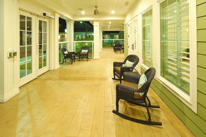 A well-lit porch with rocking chairs, providing a cozy and inviting outdoor seating area at night.