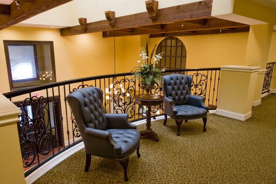 A cozy lobby area with two tufted chairs, a small table, and decorative railings.