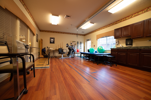 A spacious physical therapy room equipped with exercise tools and a warm atmosphere.