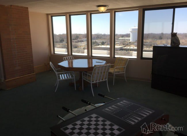 A bright room featuring a dining table with chairs, large windows, and a foosball table.