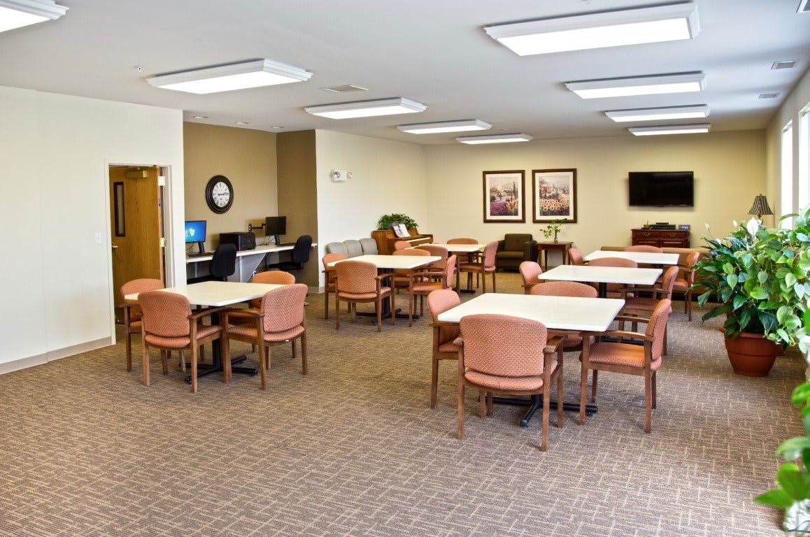 A well-lit meeting room with multiple tables and chairs arranged for gatherings.