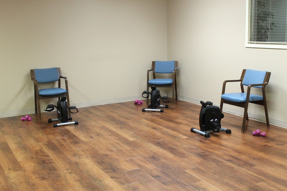 A small exercise room with chairs and stationary pedal machines on a wooden floor.