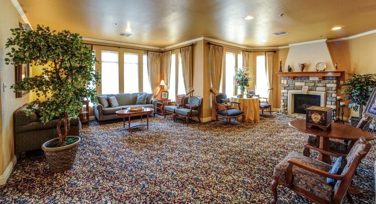 A spacious and elegantly decorated living room with multiple seating areas, luxurious curtains, and a patterned carpet.