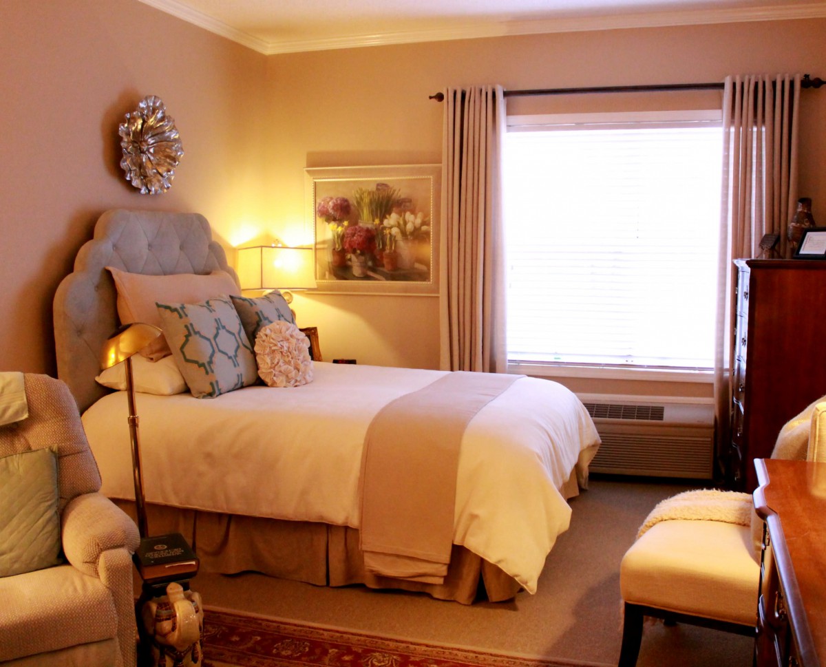 A cozy bedroom with elegant decor, featuring a neatly made bed, soft lighting, and muted colors.