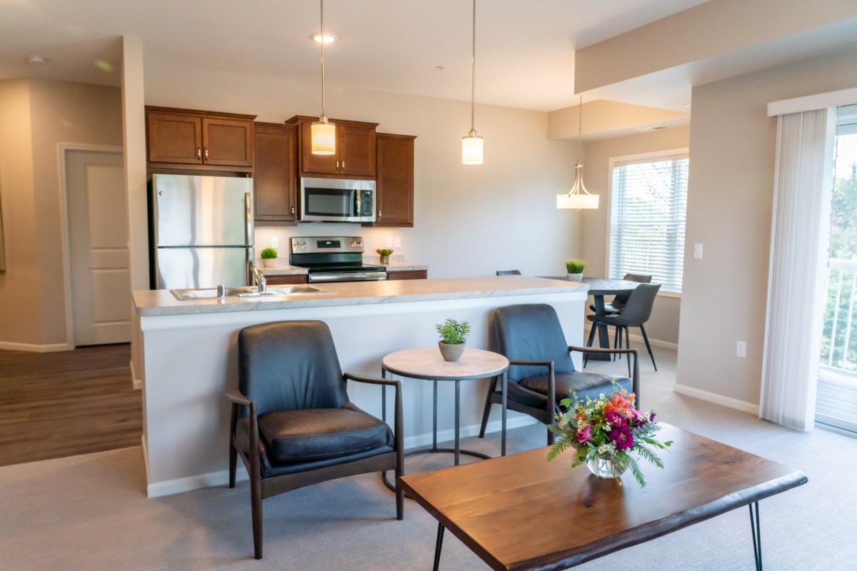 A modern open-concept kitchen and living room with stylish furniture and stainless steel appliances.
