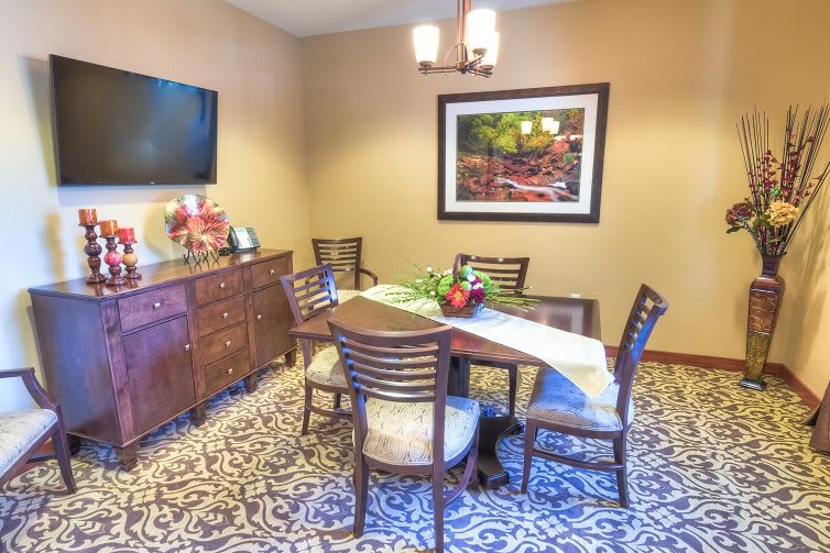 A cozy dining room setup with a table, chairs, wall art, and a television.