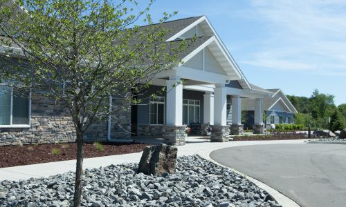 A modern building with a landscaped entrance and stone accents.