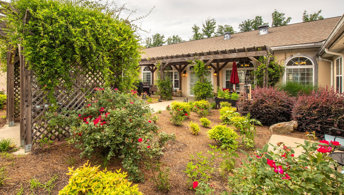 A beautifully landscaped garden with colorful flowers and shrubs surrounding a patio with a pergola.