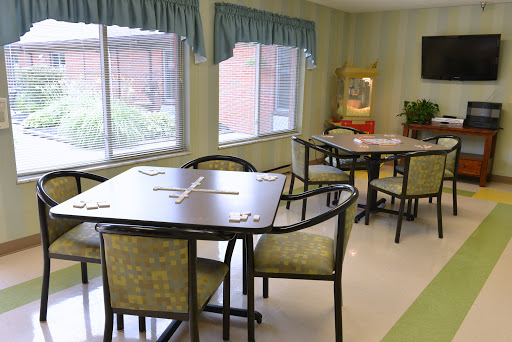 A bright and inviting dining area with tables and chairs, featuring large windows and decorative curtains.