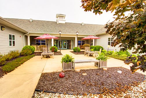 A well-maintained outdoor patio with seating and umbrellas, surrounded by landscaping.