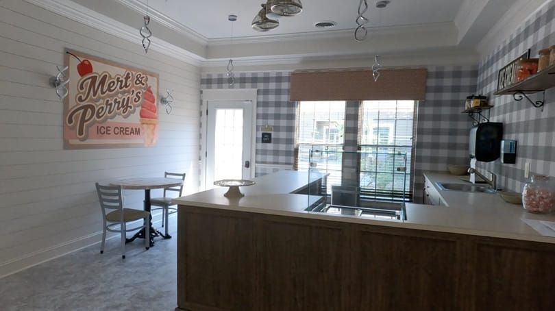 A modern kitchen with a central counter, plaid wallpaper, and natural lighting from large windows.