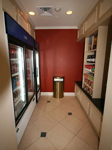 A modern pantry area featuring beverage coolers and snack shelves against a vibrant red wall.