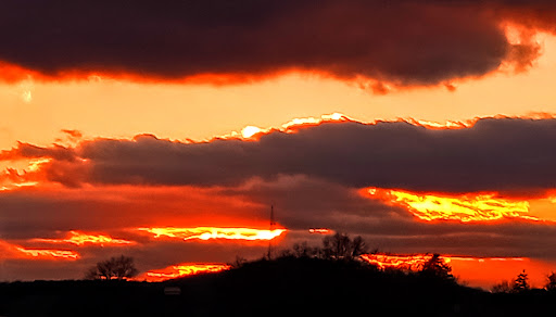 A breathtaking sunset paints the sky with vibrant hues of orange and red, framed by dark clouds.