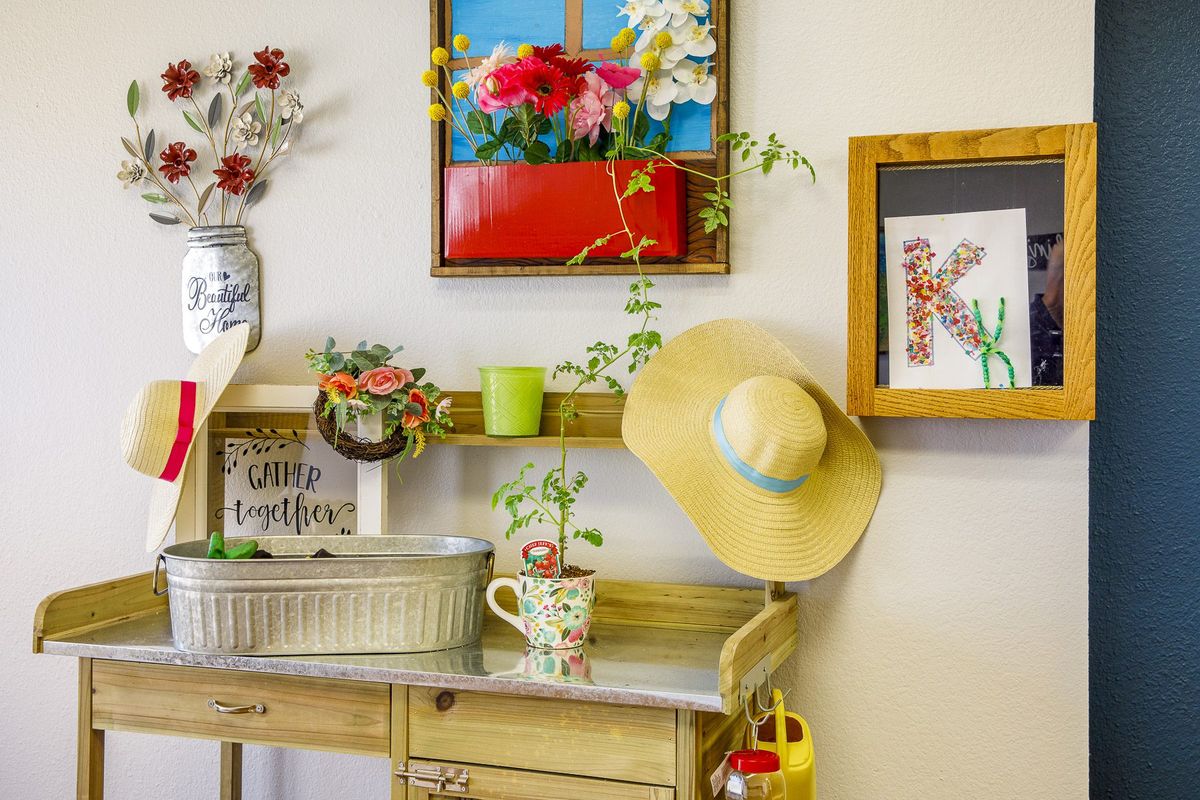 A charming vintage-style interior setup featuring floral decor, various artworks, and a sun hat hanging on the wall.