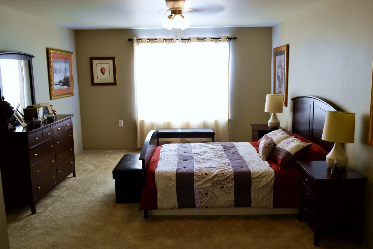 A cozy and well-lit bedroom with a neatly made bed, side tables, and decorative artwork.