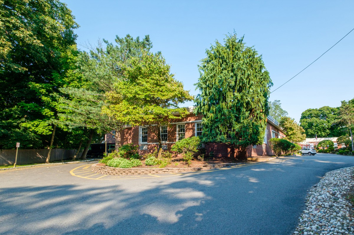 A charming brick house surrounded by trees on a sunny day.