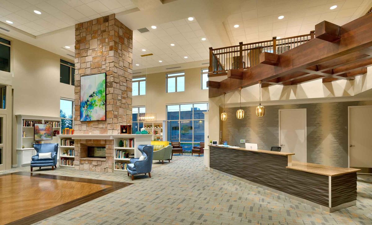 A modern and stylish lobby featuring a reception desk, comfortable seating, a fireplace, and contemporary artwork.