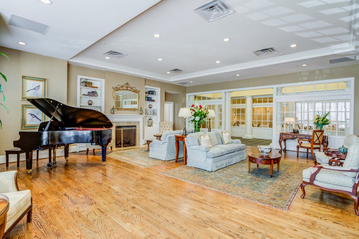 A spacious and elegantly decorated living room featuring a grand piano, comfortable seating, and a cozy fireplace.