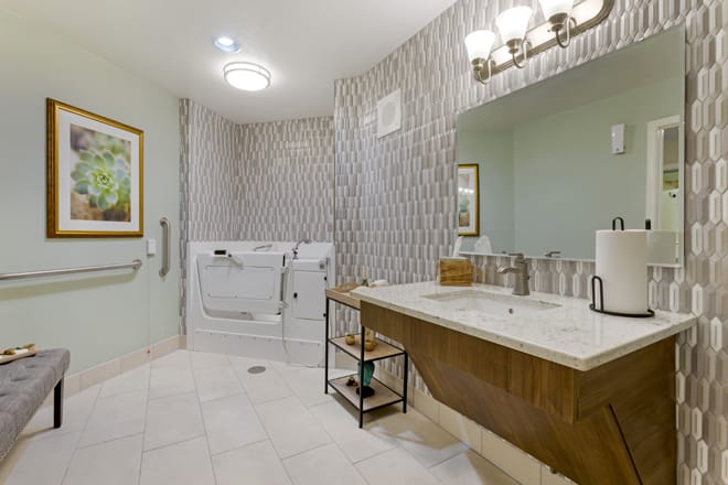 A modern bathroom with a walk-in bathtub, large mirror, and stylish lighting.
