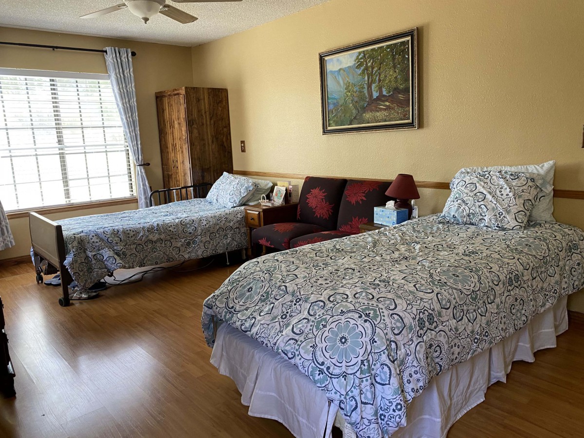 A cozy bedroom with two beds, a sofa, a window with curtains, and a painting on the wall.