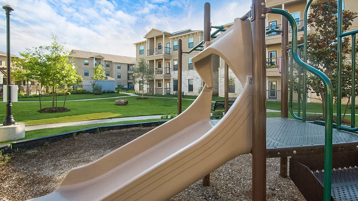 A playground slide in front of apartment buildings on a sunny day.