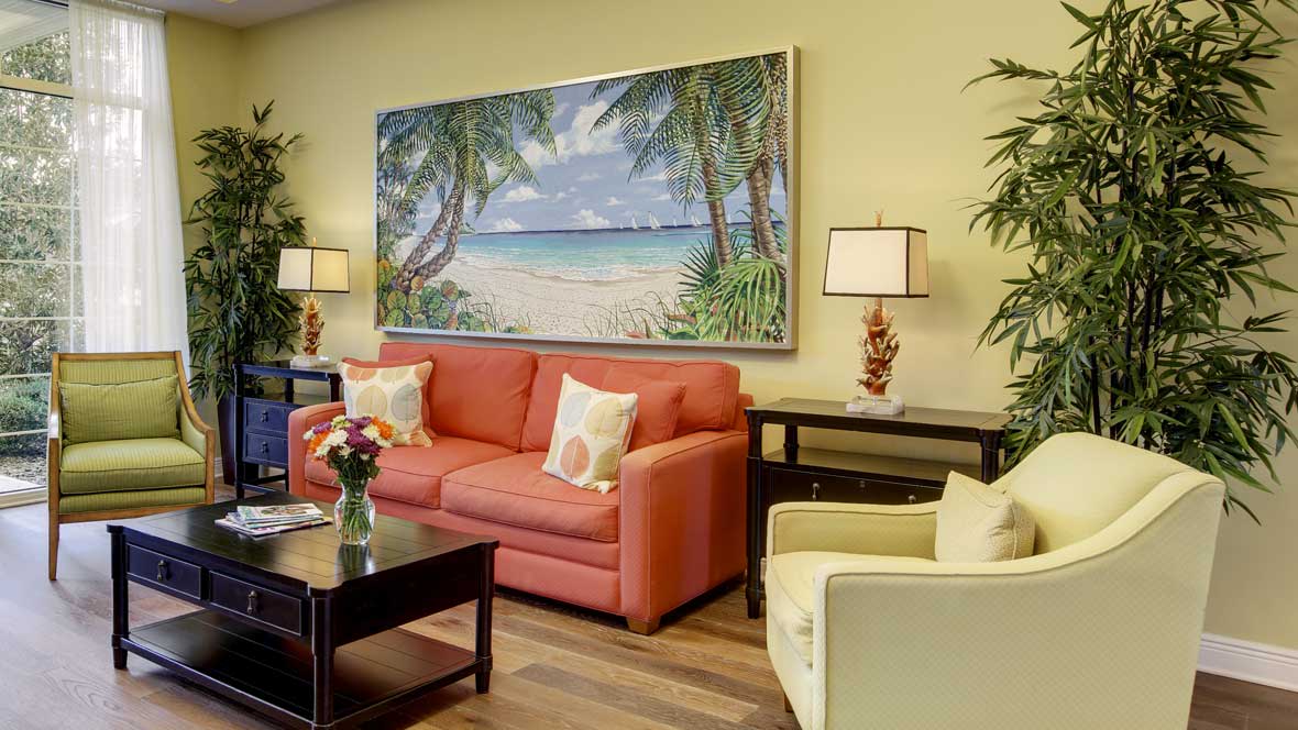A cozy living room featuring a coral sofa and a beach-themed painting on the wall.