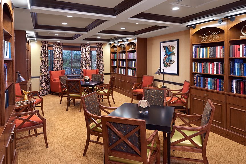 A cozy library reading room with bookshelves, tables, and comfortable chairs.
