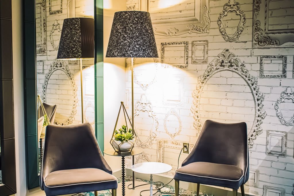 A modern interior space featuring two chairs, a decorative lamp, and artistic wall decor.