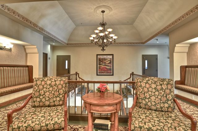 A cozy interior seating area with patterned chairs, a small table, and a chandelier overhead.