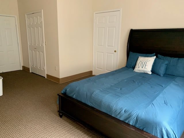 A neatly arranged bedroom with a blue bedspread and minimalist decor.