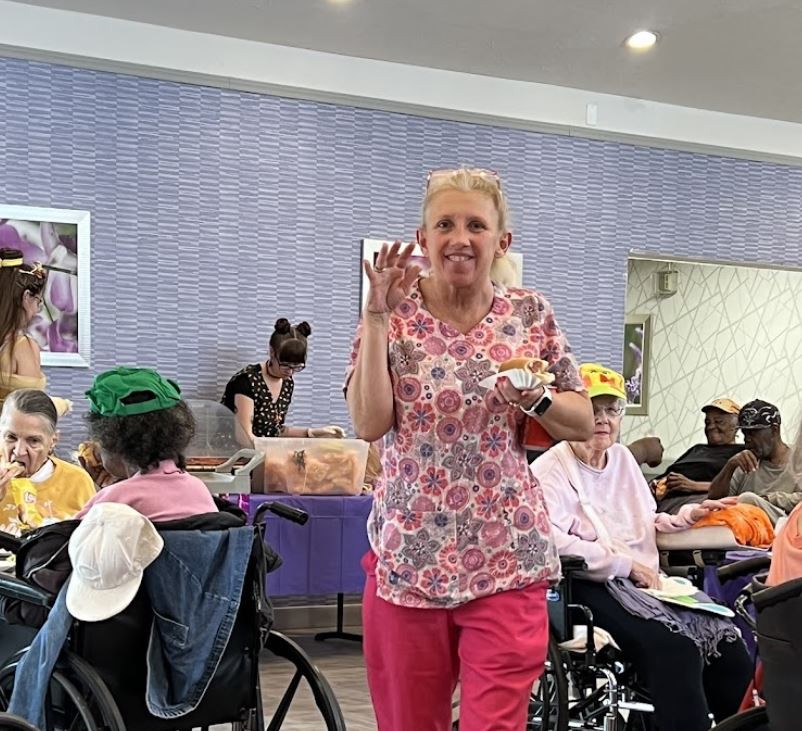 A caregiver interacts with residents at a nursing home during a social activity.