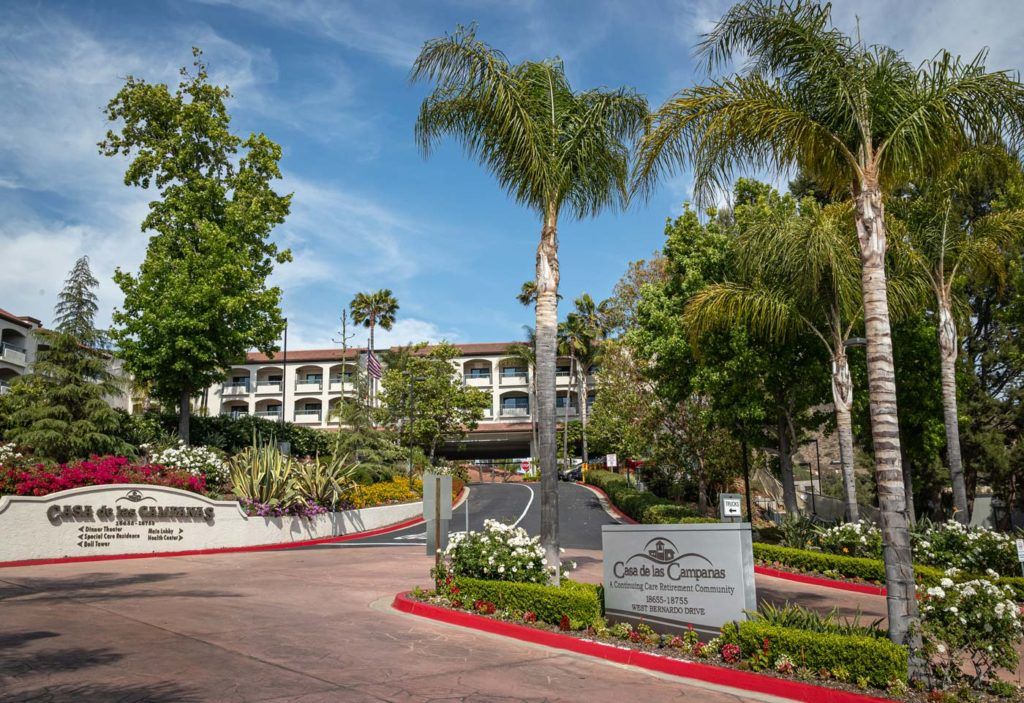 Entrance to a luxurious hotel surrounded by lush landscaping and palm trees.