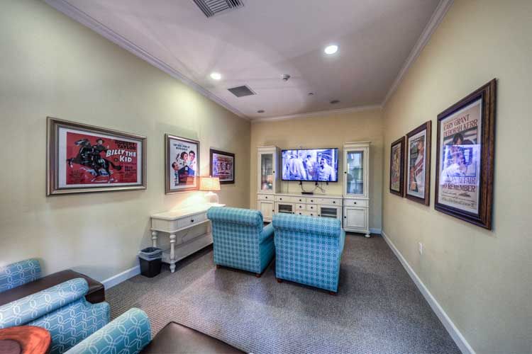 A cozy living room with comfortable seating, a large television, and framed artwork on the walls.
