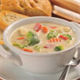 A bowl of creamy vegetable soup with a side of bread.