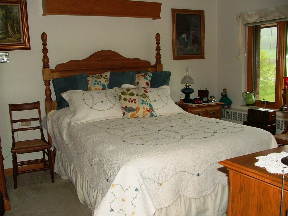 A cozy bedroom with a wooden bed frame, adorned with decorative pillows and a quilt.