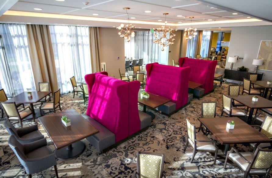 A modern restaurant interior with vibrant pink seating and elegant chandeliers.