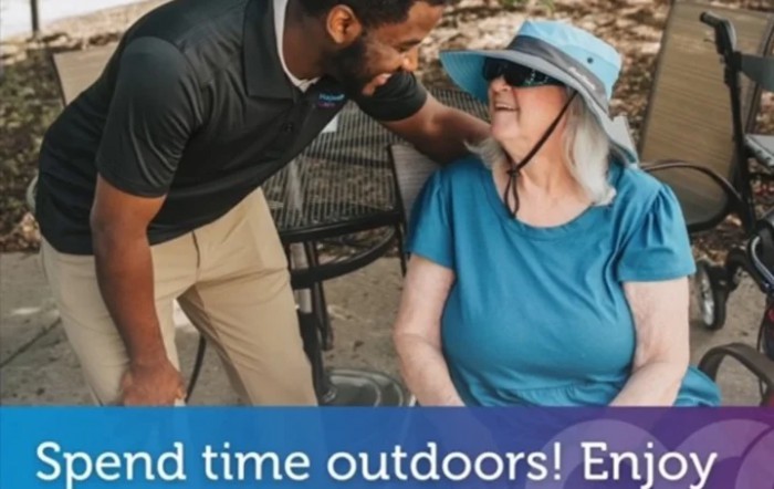 A caregiver interacting with an elderly woman outdoors.