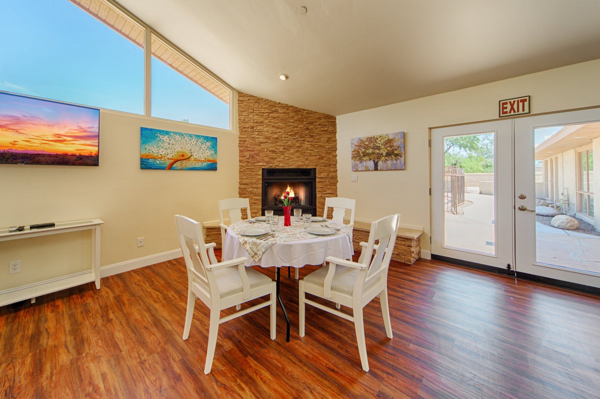 A cozy dining room with a round table set for four, featuring a fireplace and hardwood floors.