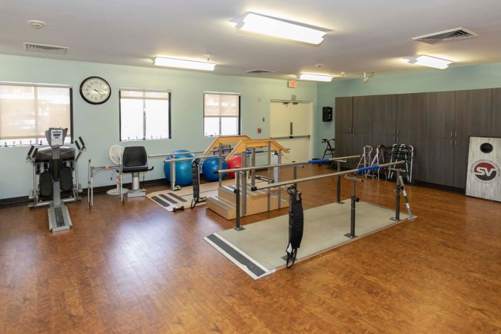 A well-equipped physical therapy room featuring parallel bars and exercise tools.