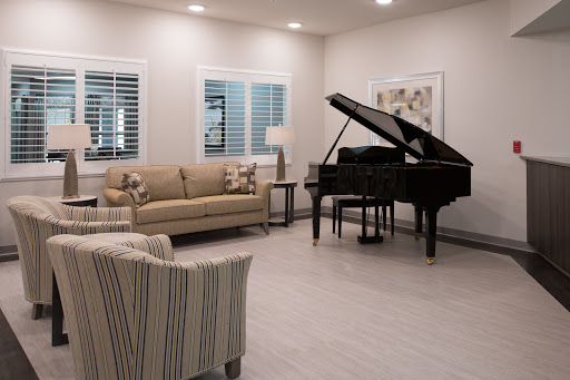 A cozy living room featuring a grand piano, stylish seating, and warm lighting.