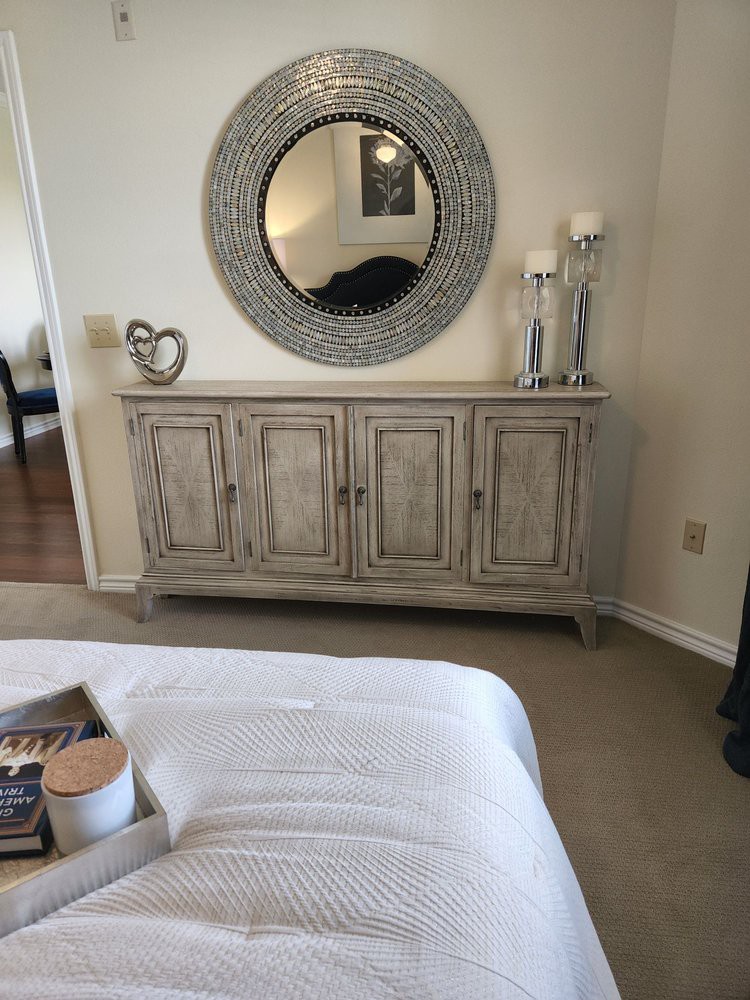 A cozy bedroom featuring a decorative dresser topped with candles and a large round mirror.