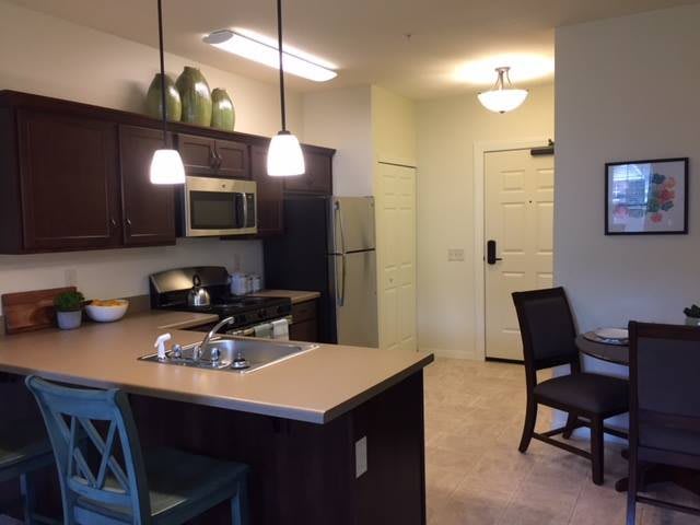 Modern kitchen with dining area featuring contemporary lighting and appliances.