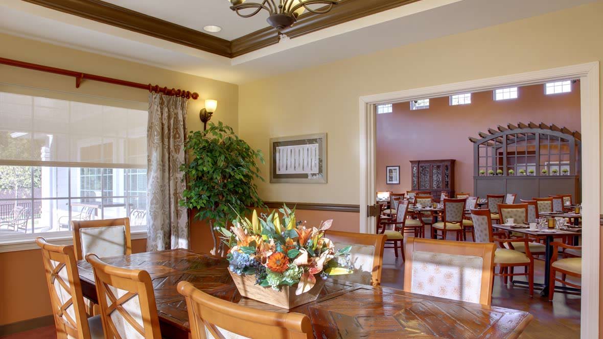 A well-decorated dining room featuring a wooden table, chairs, floral arrangement, and elegant lighting.