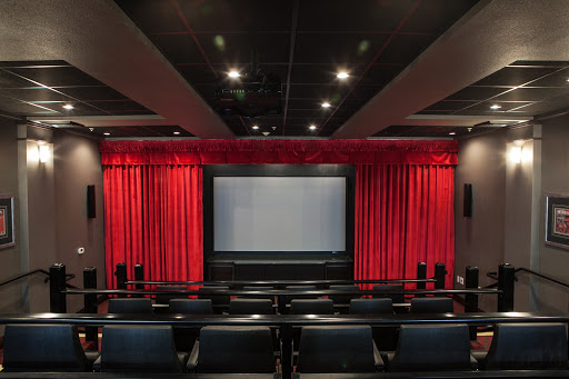 A cozy home theater setup featuring a large screen and plush seating with elegant red curtains.