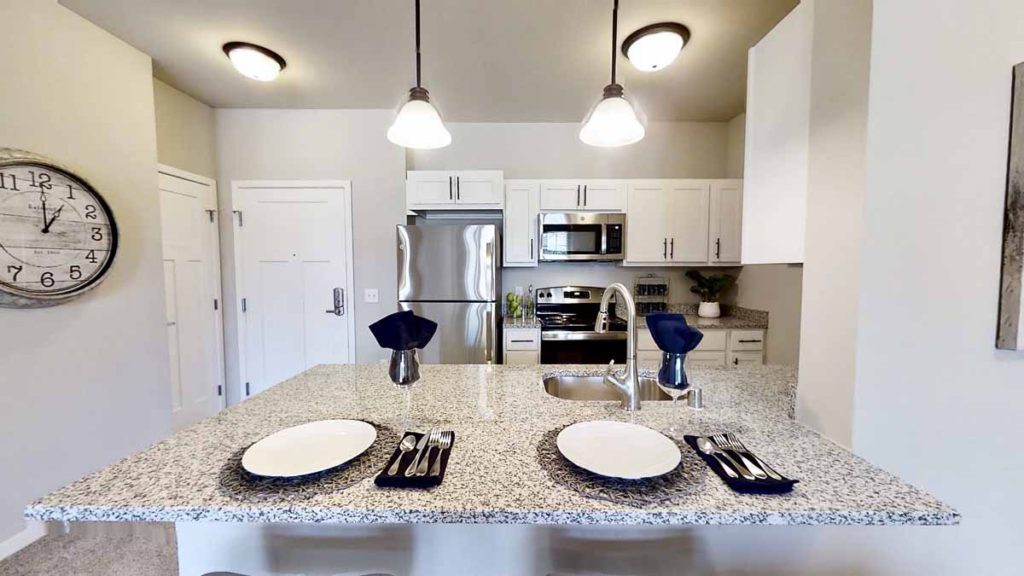 Modern kitchen with a dining setup on the countertop and stainless steel appliances.