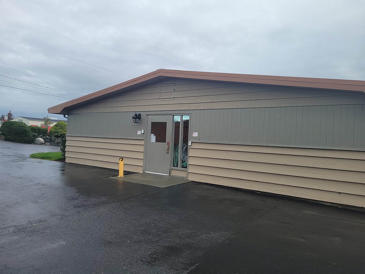 A small building with a slanted roof on a cloudy day.